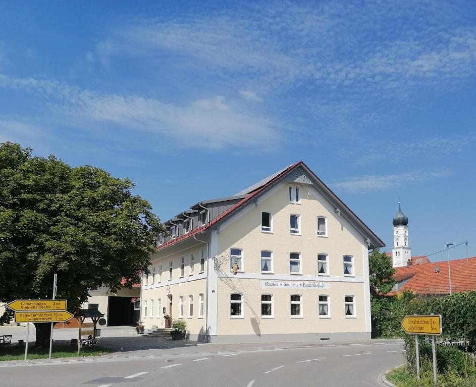a large white building with a clock tower in the background at Pension zum Bären in Langerringen