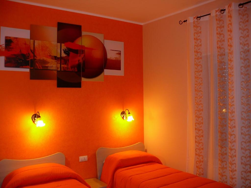 メッシーナにあるB&B Maxのオレンジ色の壁の客室内のベッド2台