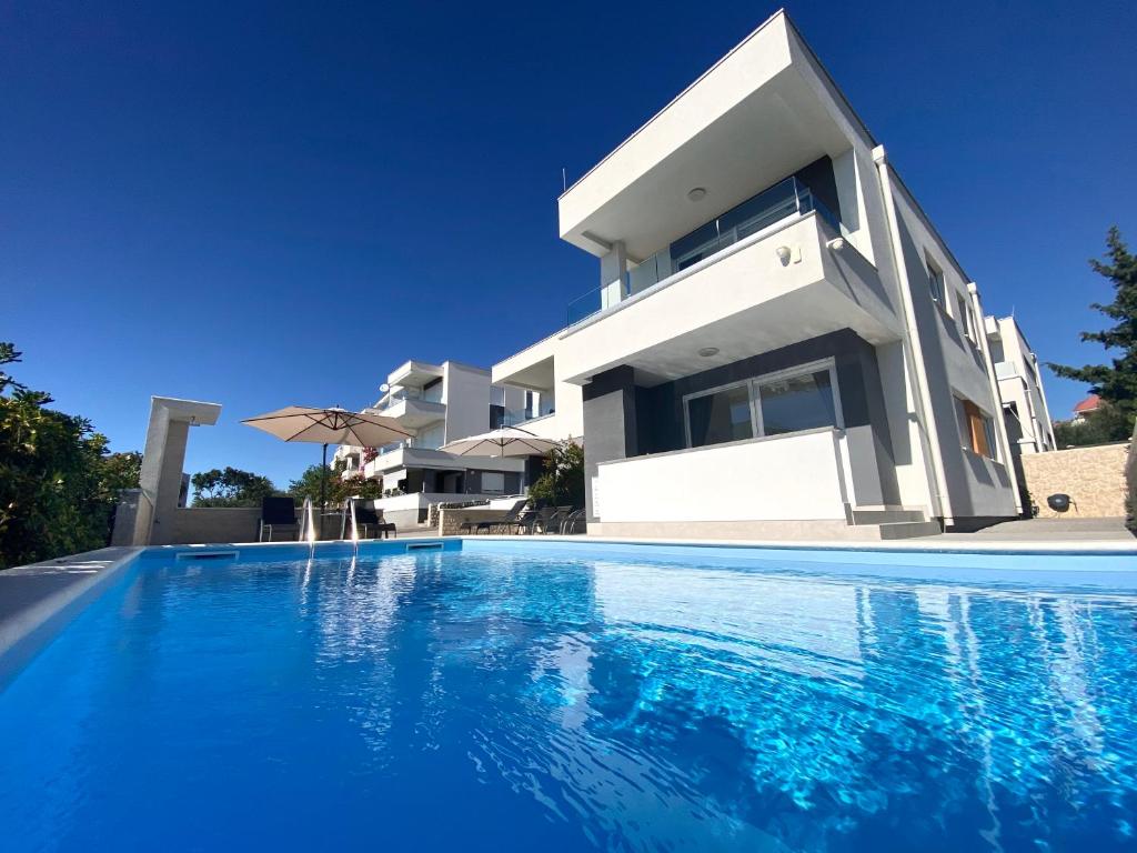 a villa with a swimming pool in front of a house at Fantasy Pool Villa in Novalja