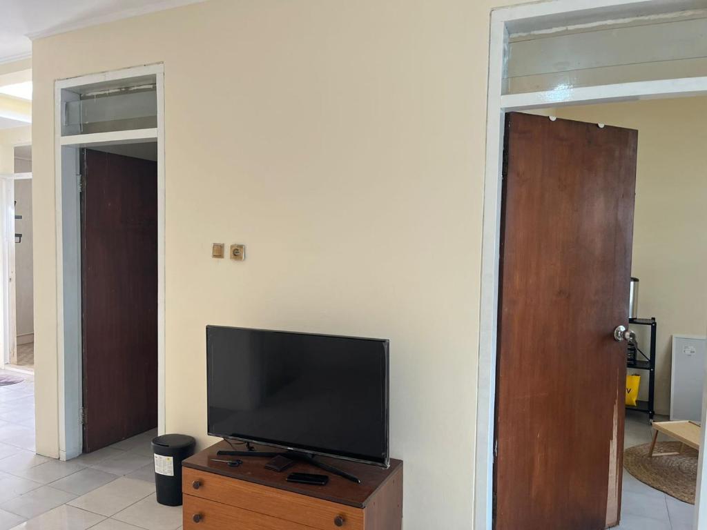 a flat screen tv sitting on top of a wooden dresser at Minyo Guest House in Jakarta