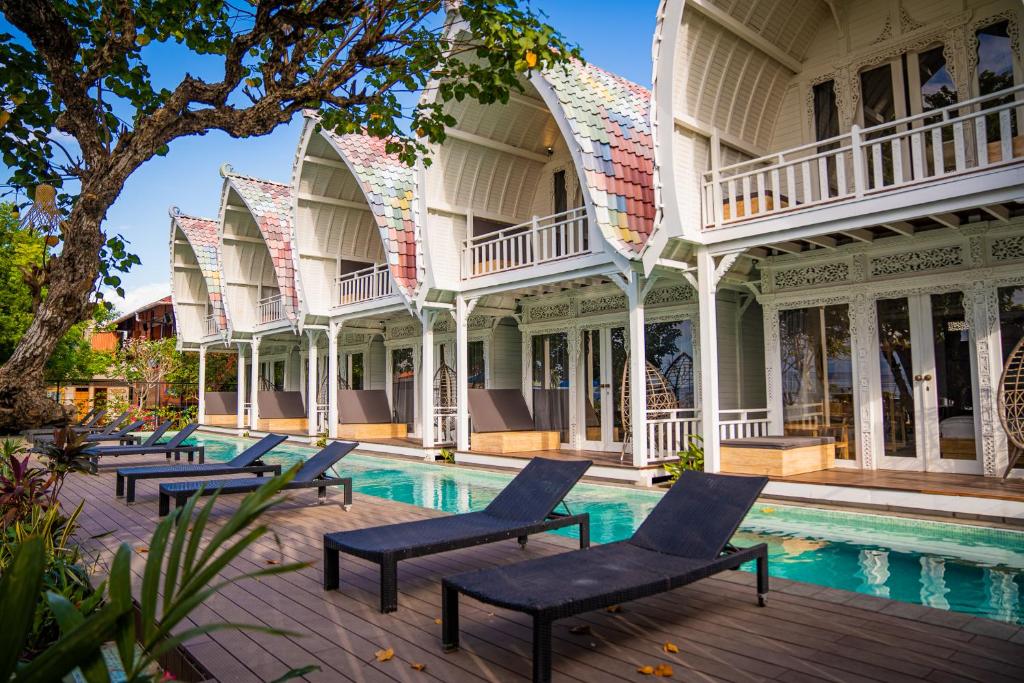 an old mansion with chairs around a swimming pool at Mambo Beach Resort in Nusa Penida