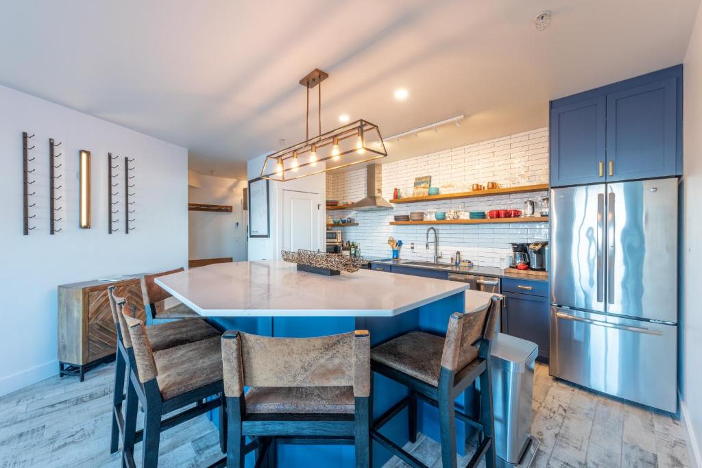 una cocina con una isla azul con sillas y nevera en Fully Renovated Ski-in/out Loft with Private Hot Tub!, en Golden