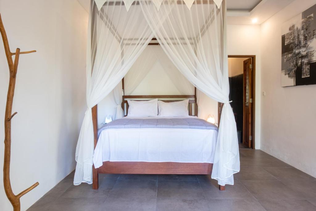 Schlafzimmer mit Himmelbett und weißen Vorhängen in der Unterkunft Variegata Private Villa Ubud by Supala in Ubud