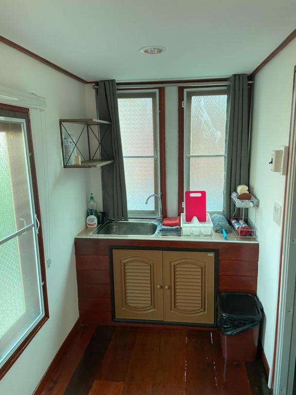 a small kitchen with a sink and two windows at Lampang Hideaway Guesthouse in Lampang