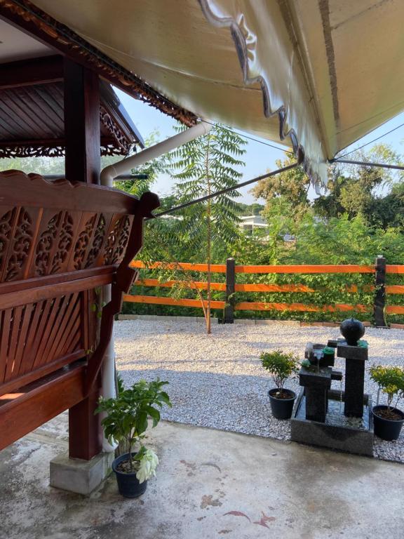 a patio with a wooden bench and potted plants at Lampang Hideaway Guesthouse in Lampang