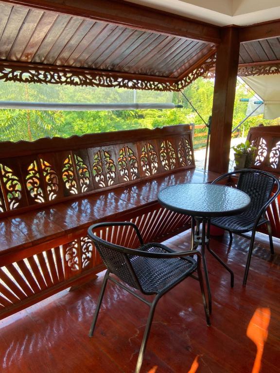 a patio with tables and chairs on a porch at Lampang Hideaway Guesthouse in Lampang