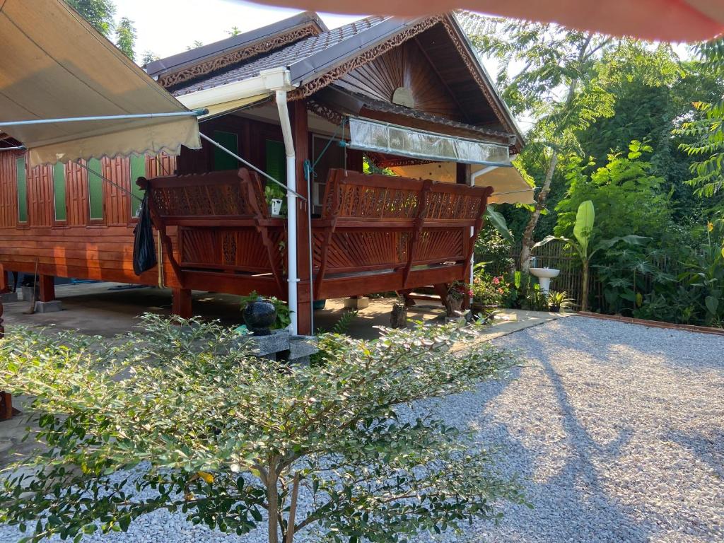 a house with two wooden benches in a yard at Lampang Hideaway Guesthouse in Lampang