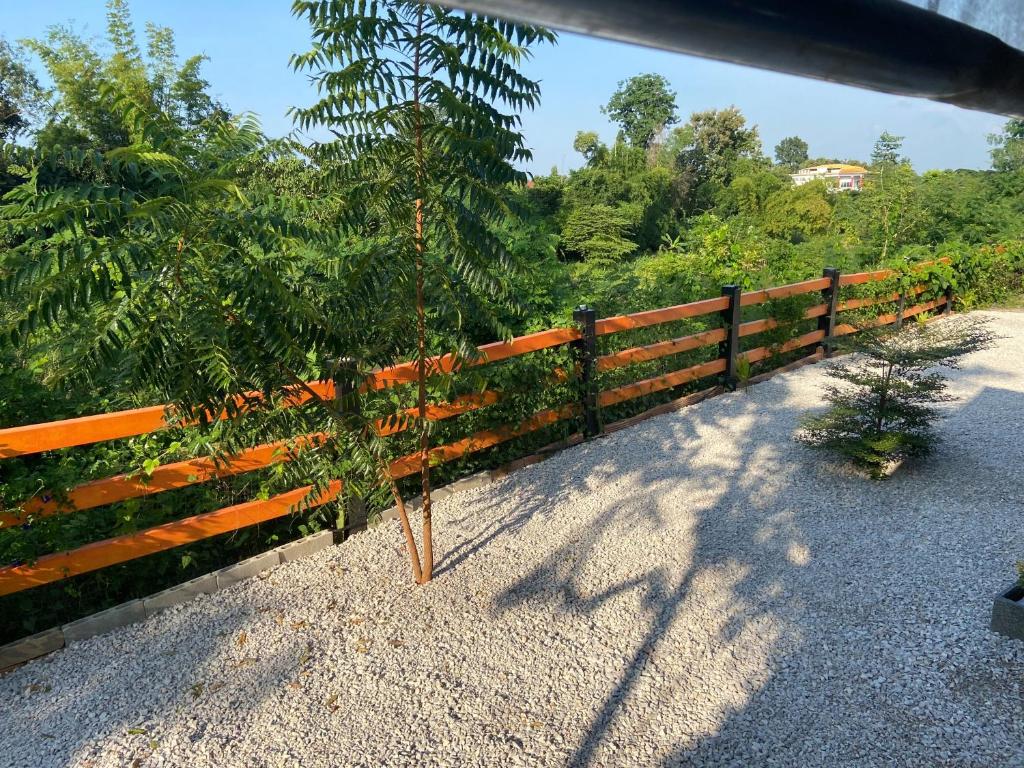 a wooden fence next to a road with trees at Lampang Hideaway Guesthouse in Lampang
