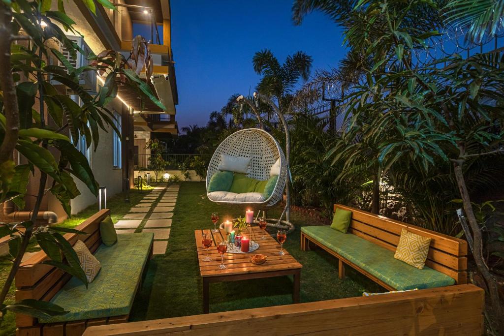 a patio with a table and a bench and a chair at SaffronStays Casa Delizia, Lonavala in Lonavala