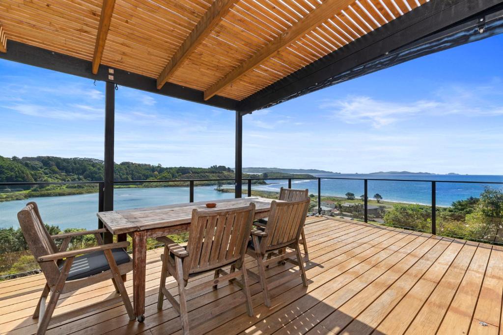 um deque de madeira com uma mesa e cadeiras e o oceano em Tapuaetahi Beach Marvel - Te Tii Holiday Home em Waipapa