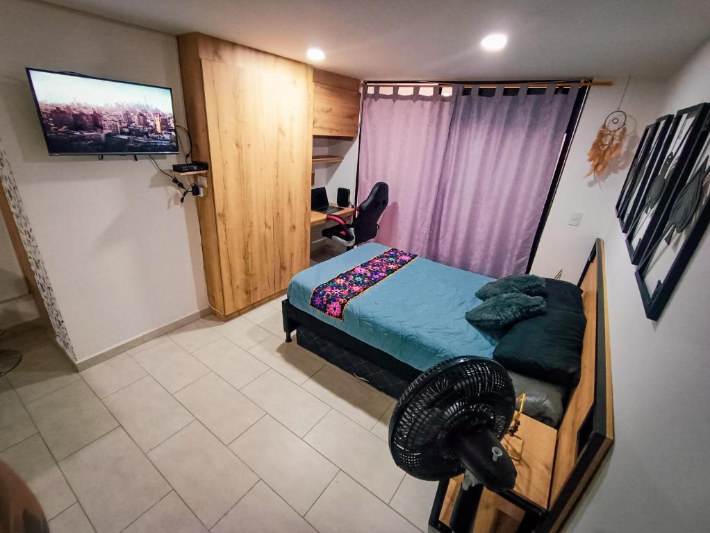 1 dormitorio con 1 cama y TV de pantalla plana en Acogedor loft frente al tranvía, en Medellín