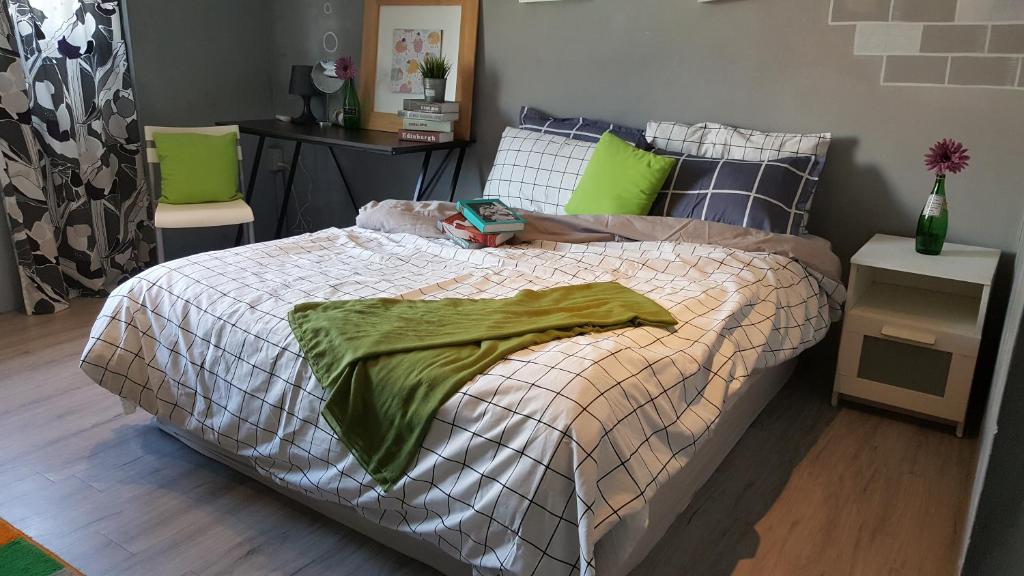 Rabbit芮比特 في كنتيج: غرفة نوم مع سرير مع بطانية خضراء عليه
