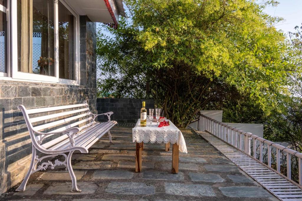 un banco de madera sentado en un patio con una mesa en StayVista at Meraki Homestay - 2BR Pet Friendly Villa in Dharamshala, en Dharamshala
