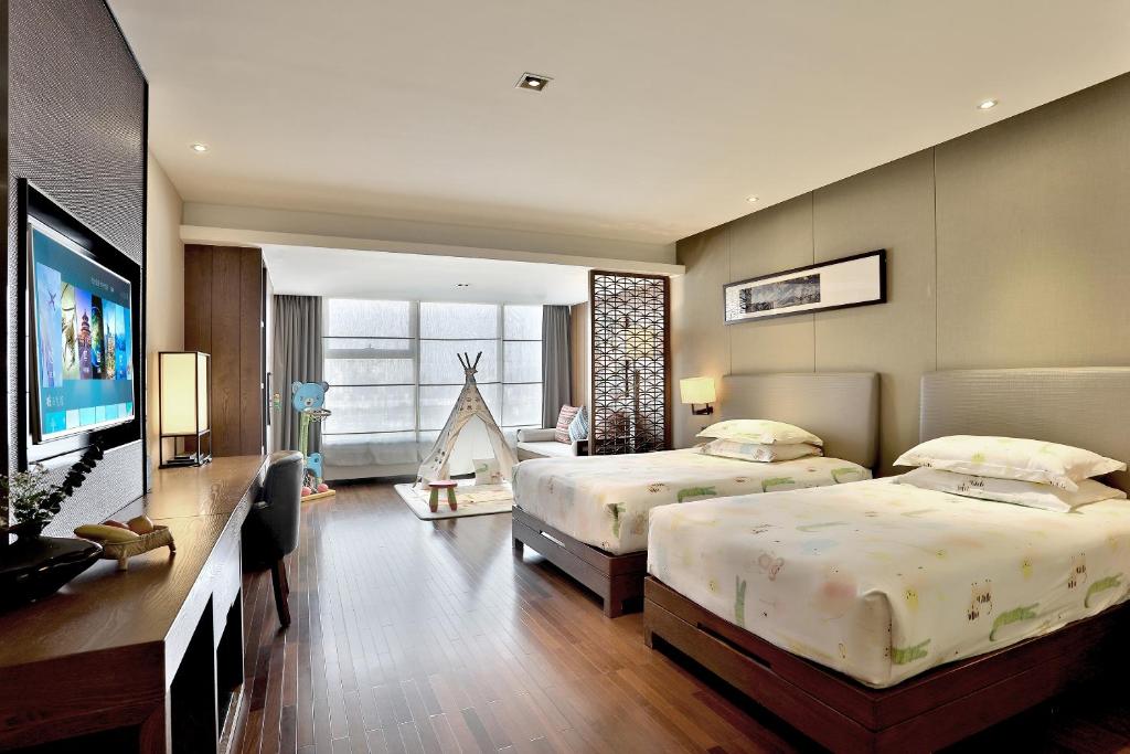 a bedroom with two beds and a flat screen tv at SSAW Boutique Hotel Hangzhou Wildwind in Hangzhou