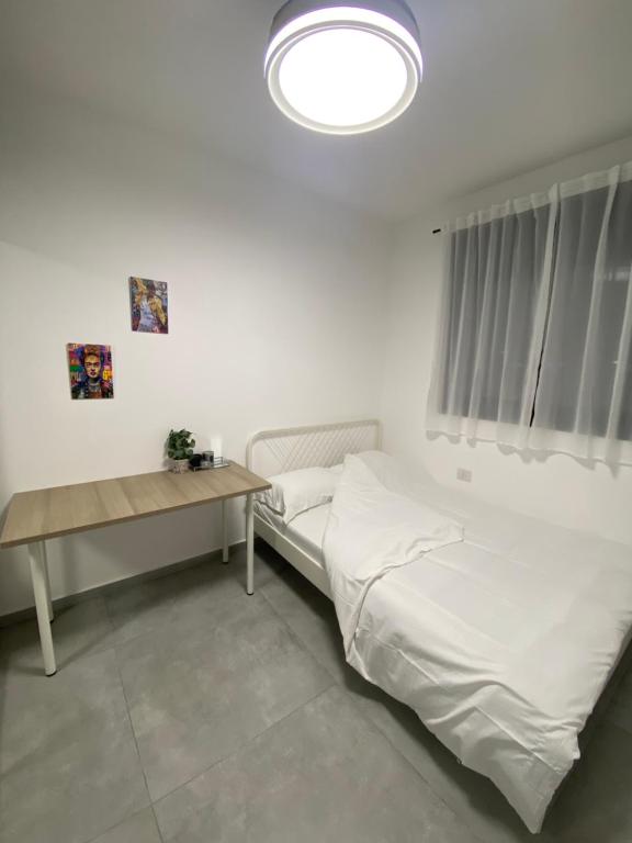 a white bedroom with a bed and a table at אמור in Beer Sheva