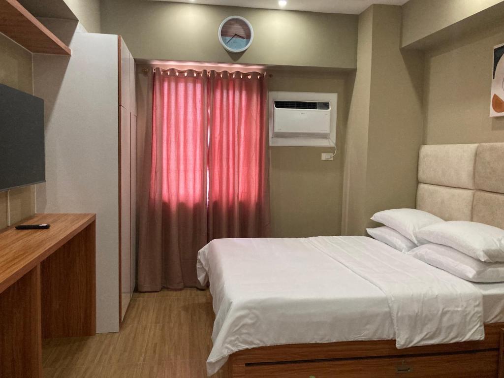 um pequeno quarto com uma cama e uma cortina vermelha em 1523 MIGAs Haven at Sunvida across SM City em Cebu