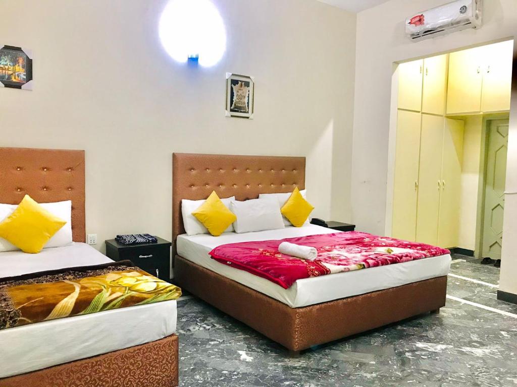 um quarto com 2 camas com lençóis amarelos e vermelhos em HOTEL ROSE INN em Lahore