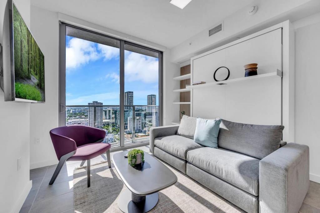 een woonkamer met een bank en een groot raam bij Modern 1 Bed Condo across from Bayside in Downtown in Miami