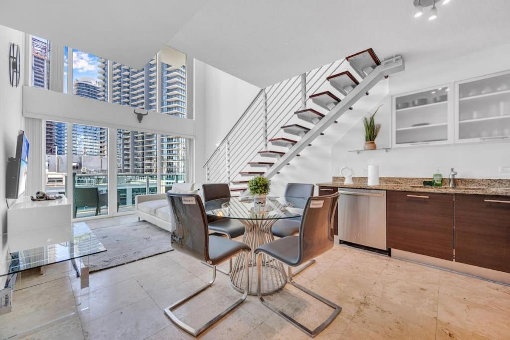a dining room with a table and chairs and a staircase at Amazing Loft style 1 Bed with Water and City Views in Miami