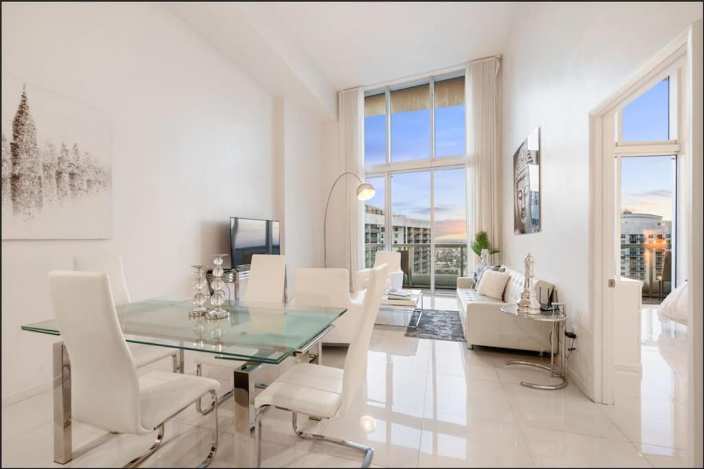 a dining room with a glass table and white chairs at Beautiful One Bedroom Condo 16ft ceilings at the W in Miami