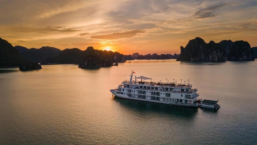 a cruise ship in the water at sunset at Paradise Elegance Cruise Halong in Ha Long