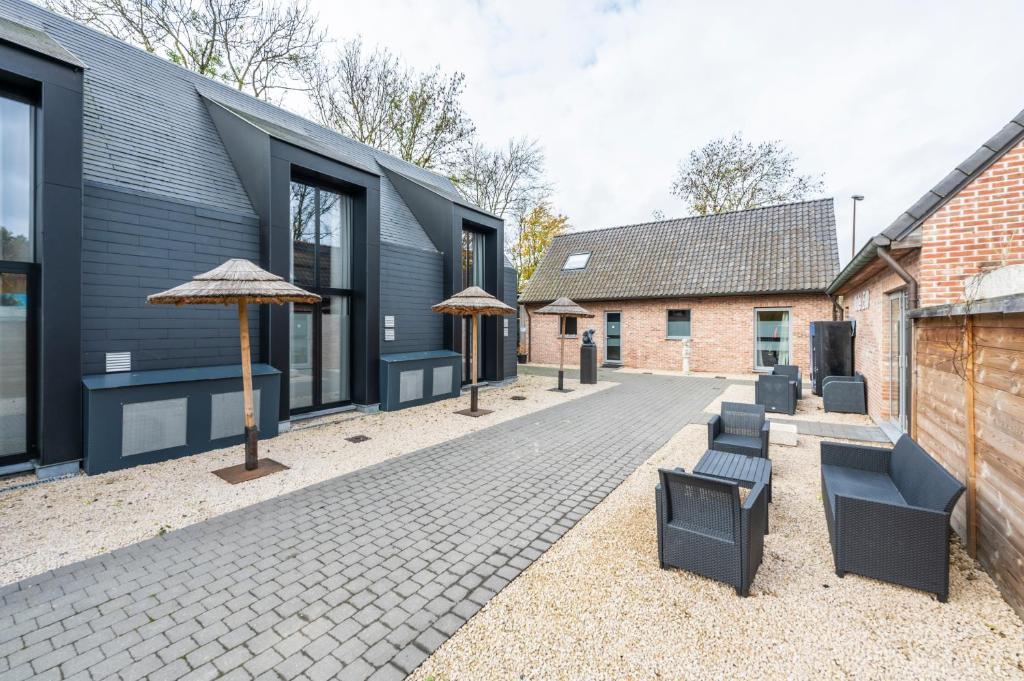 a courtyard with chairs and umbrellas next to a building at M-otel E40 in Wetteren