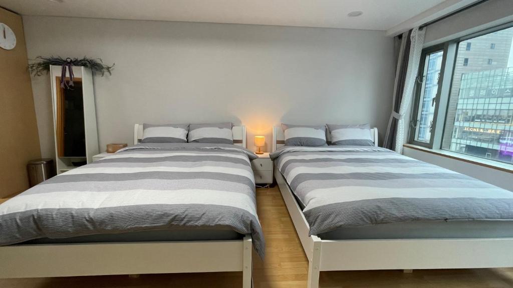 two twin beds in a room with a window at Hongdae Residence-4 - 1min from Hongik Univ Station #1 in Seoul