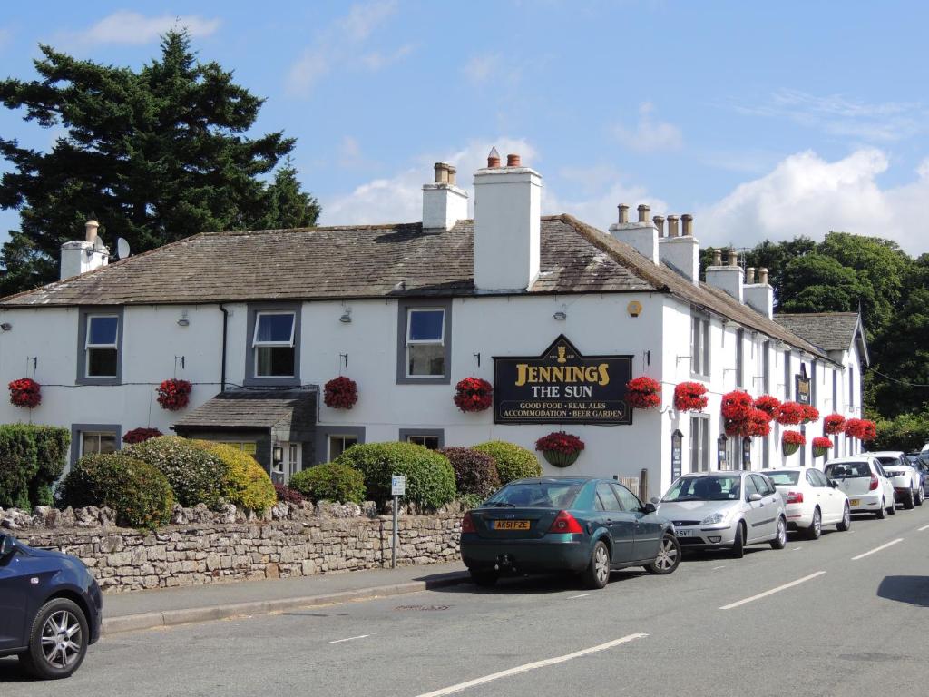 a white inn with cars parked in front of it at Sun Inn in Pooley Bridge