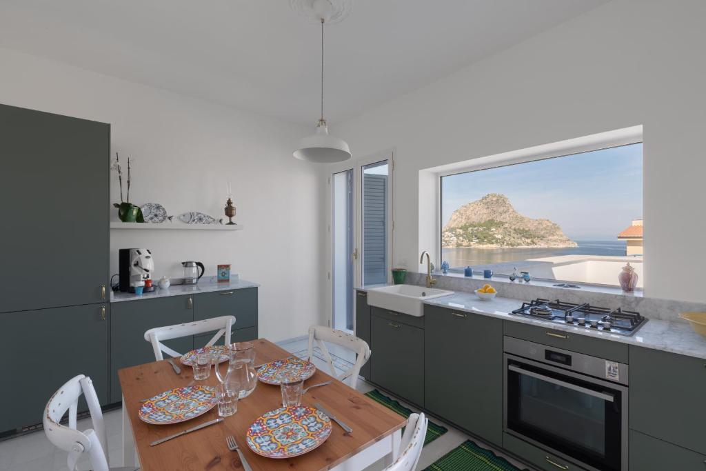 Una cocina con mesa y sillas y una ventana. en Solemar Sicilia - Casa Margherita, en Santa Flavia