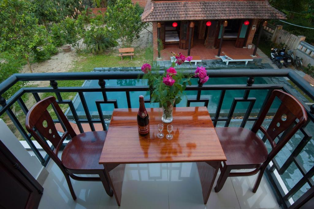 a table with a bottle of wine and flowers on a balcony at Tra Que Flower Homestay in Hoi An