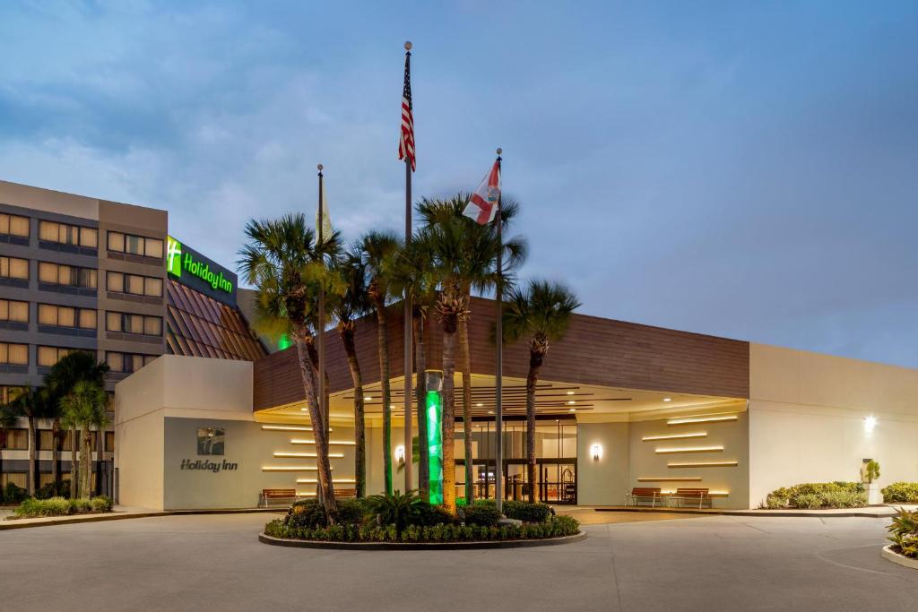 a hotel with palm trees in front of a building at Holiday Inn Orlando International Airport, an IHG Hotel in Orlando