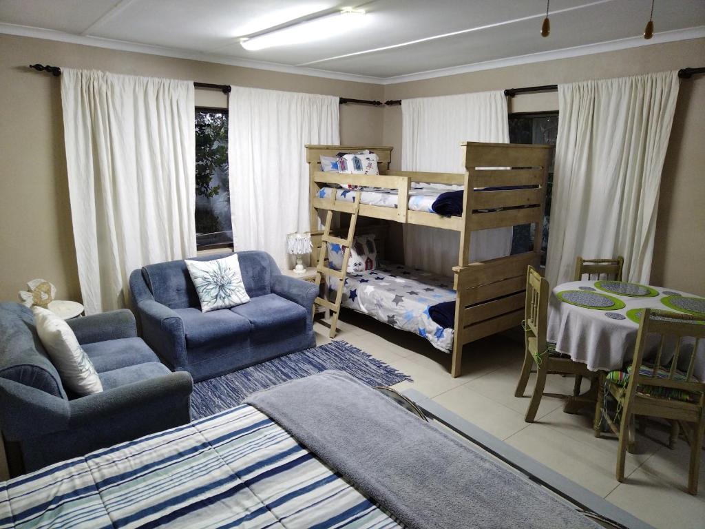 uma sala de estar com uma cama, uma mesa e cadeiras em Dollies place em Bazley Beach