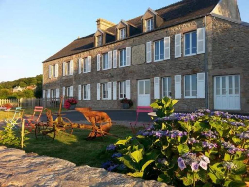 un gran edificio de ladrillo con flores delante en La Roche du Marais en Omonville-la-Petite