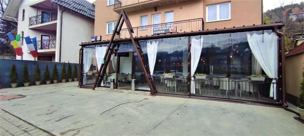 a building with a screened in porch with white curtains at EDO'S in Borşa