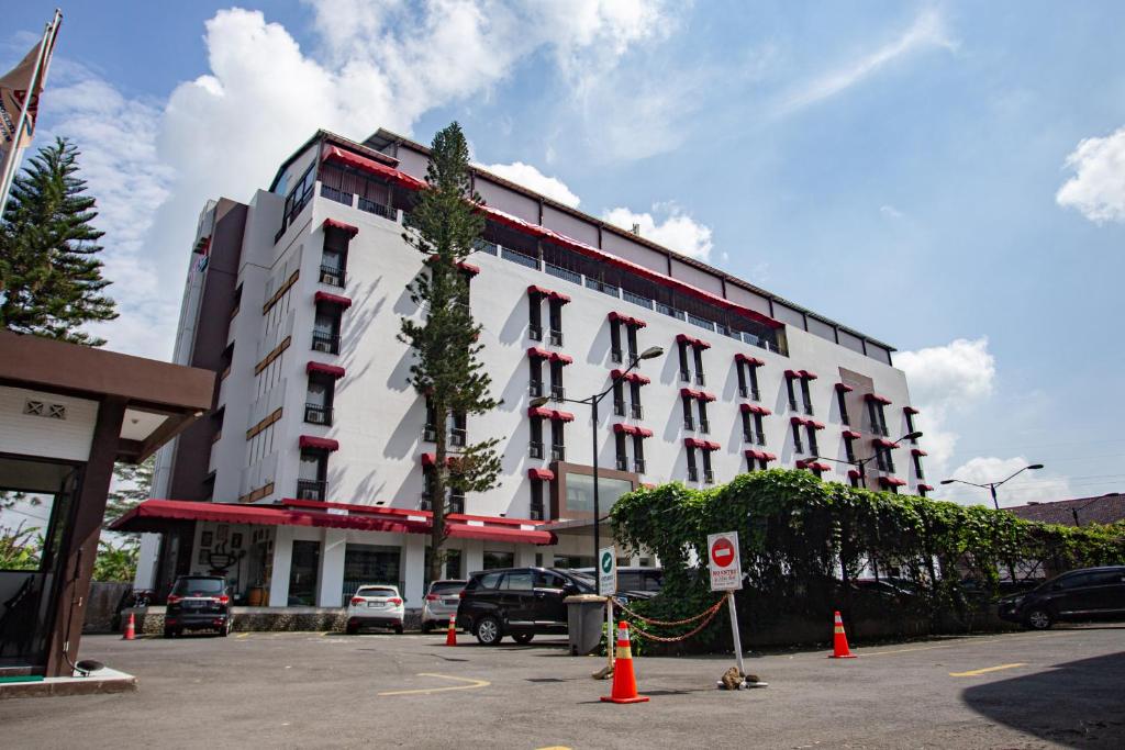 a large white building with cars parked in a parking lot at Meotel Purwokerto in Purwokerto