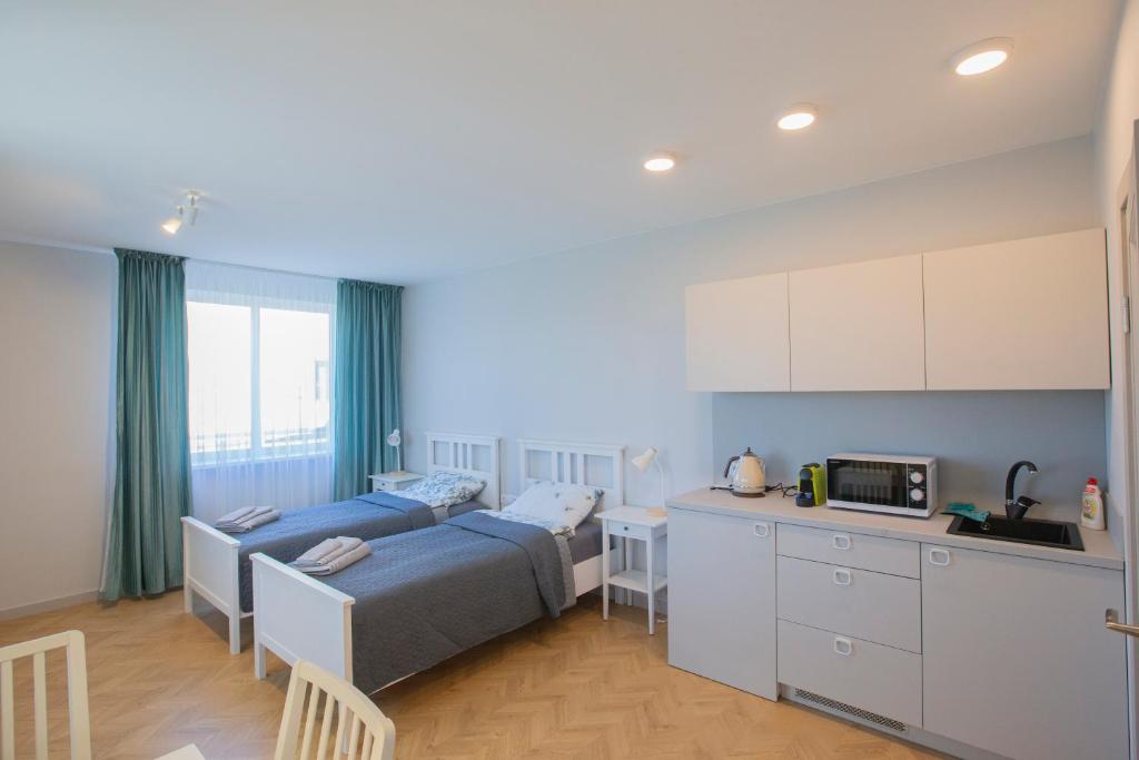 a bedroom with two beds and a kitchen in it at Apartamentai Baltas gandras in Naisiai