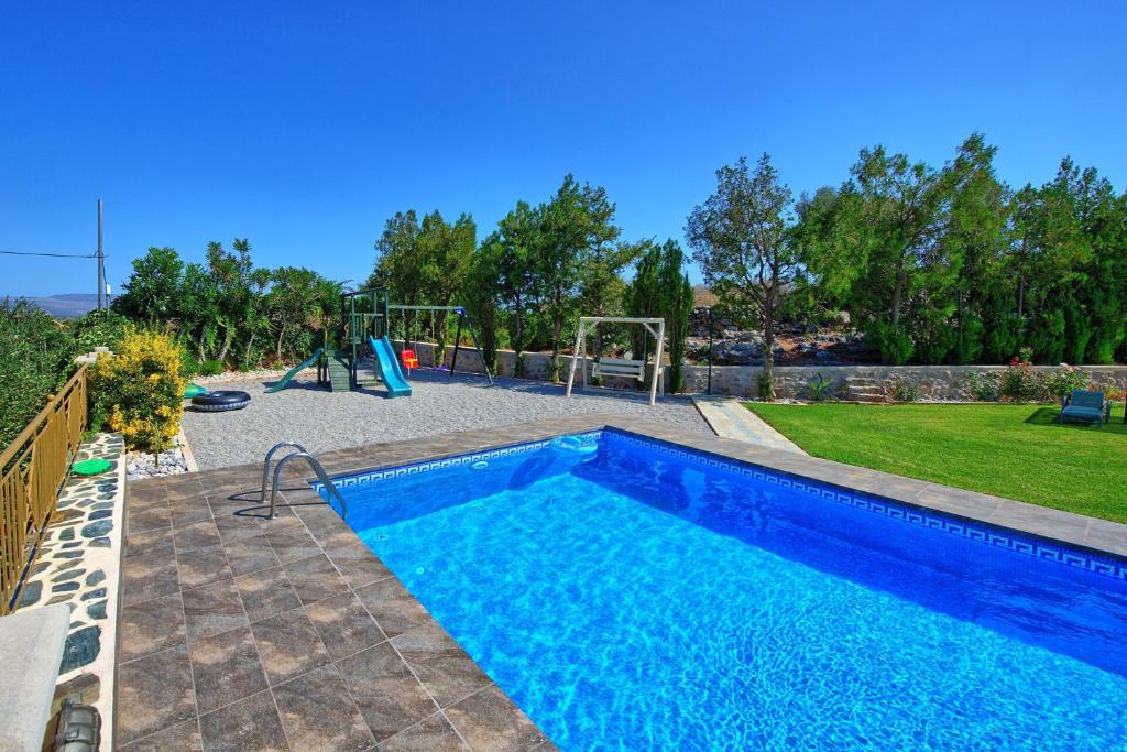 a swimming pool in a yard with a playground at Villa Gianna by PosarelliVillas in Fílippos