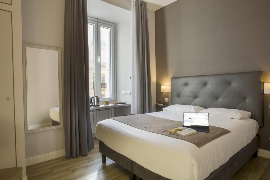 a bedroom with a large bed with a laptop on it at Colosseo Prestige Rooms in Rome