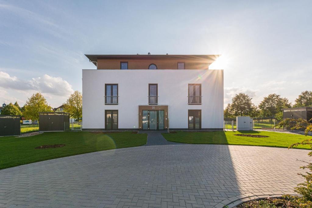 a large white house with a driveway at Luxus Spa Penthouse Sundowner in Göhren-Lebbin