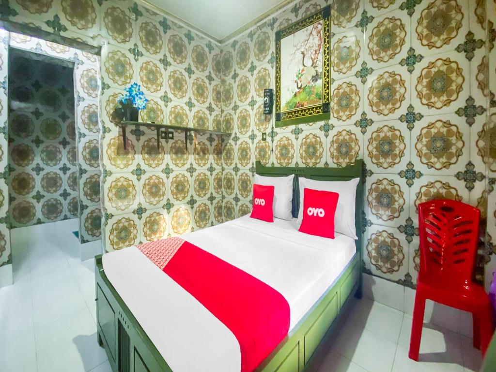 um quarto com uma cama com duas almofadas vermelhas em OYO 2518 Wilma Hotel Ii Premier em Kupang