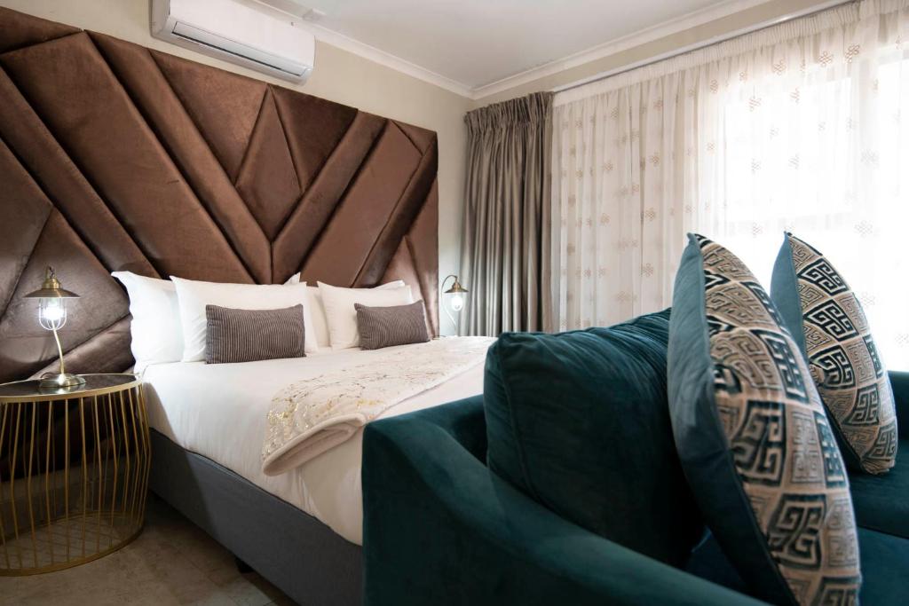 a bedroom with a large bed and a couch at Lefa Boutique Hotel in Rustenburg