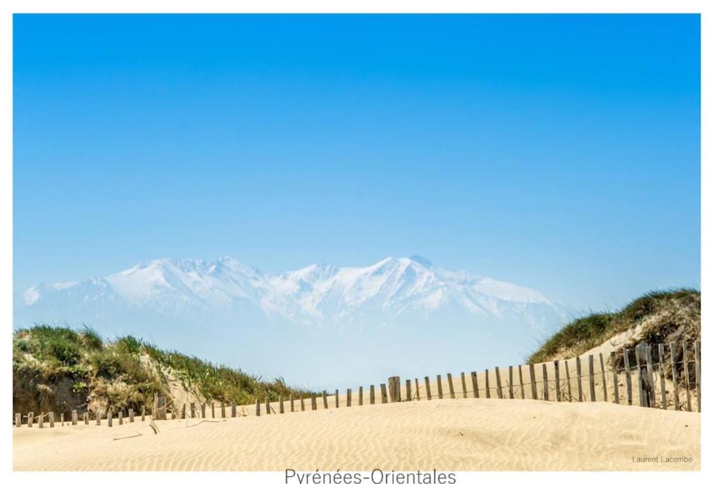 a fence on a beach with mountains in the background at Villa Alberes Sorede 7 km of beaches in Sorède