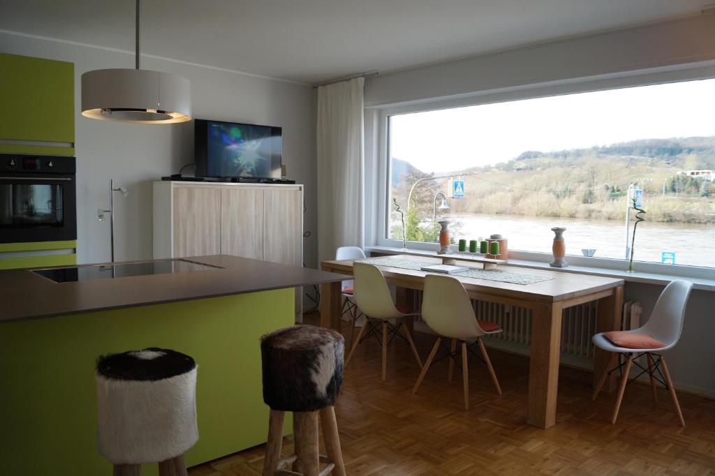 eine Küche mit einem Tisch und Stühlen sowie einem großen Fenster in der Unterkunft Ferienwohnung Moselschön in Brodenbach