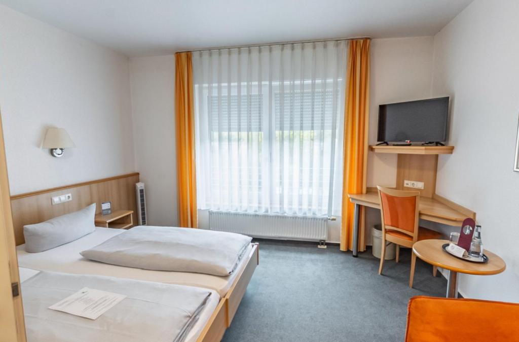 a hotel room with a bed and a desk and a television at Hotel-Gasthof zum Ritter in Haßmersheim