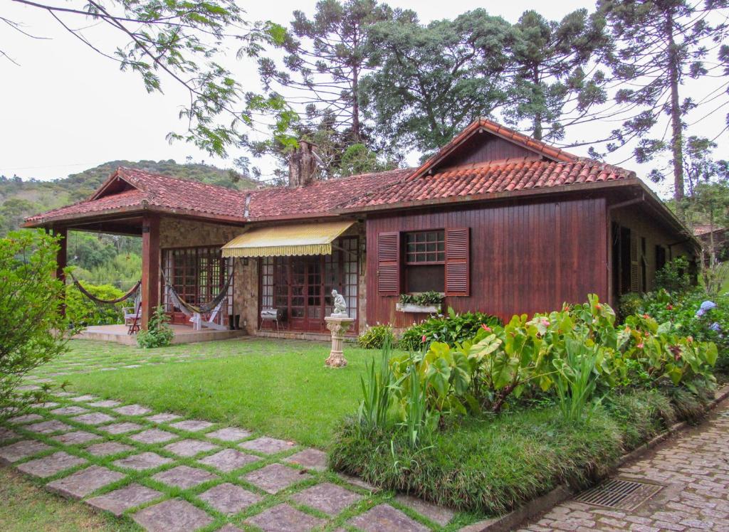 una pequeña casa con un jardín frente a ella en Casa de campo Hortencia com piscina e lazer - RJ, en Teresópolis