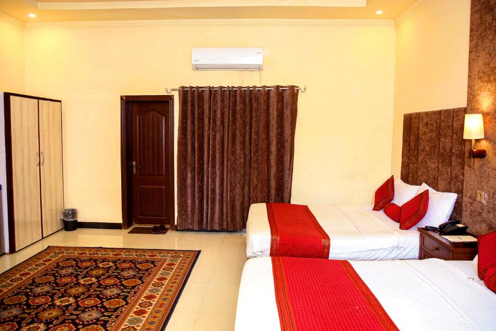 a hotel room with two beds and a door at Shelton Residency Lahore in Lahore