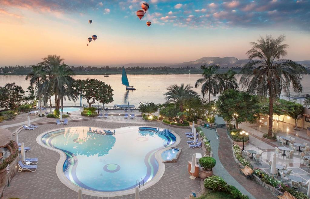 a group of hot air balloons flying over a pool at a resort at Steigenberger Nile Palace Luxor - Convention Center in Luxor