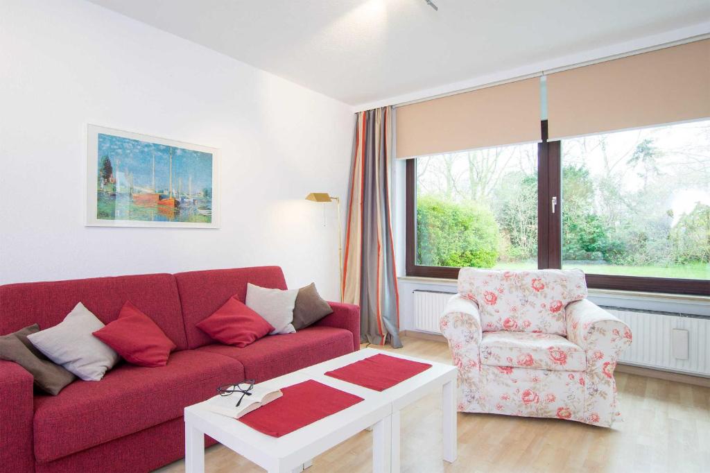ein Wohnzimmer mit einem roten Sofa und einem Stuhl in der Unterkunft MEI77 Ferienwohnung Zimmermann F in Niendorf