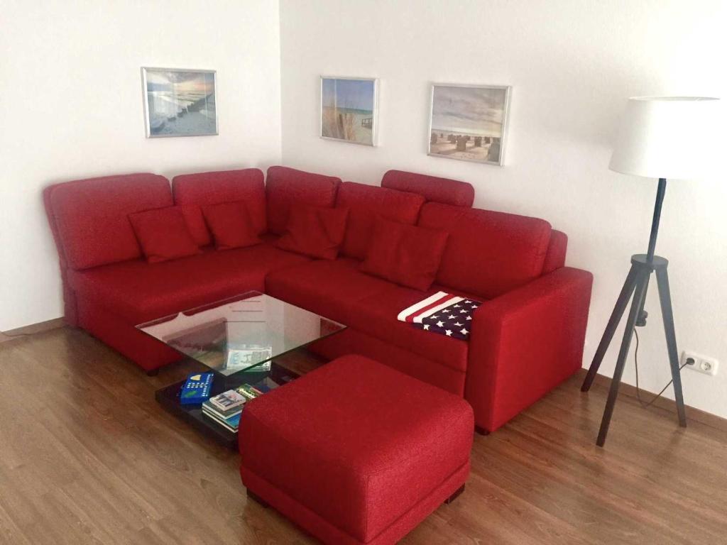 ein Wohnzimmer mit einem roten Sofa und einem Tisch in der Unterkunft OST35c Ferienwohnung Sonnendeck in Niendorf