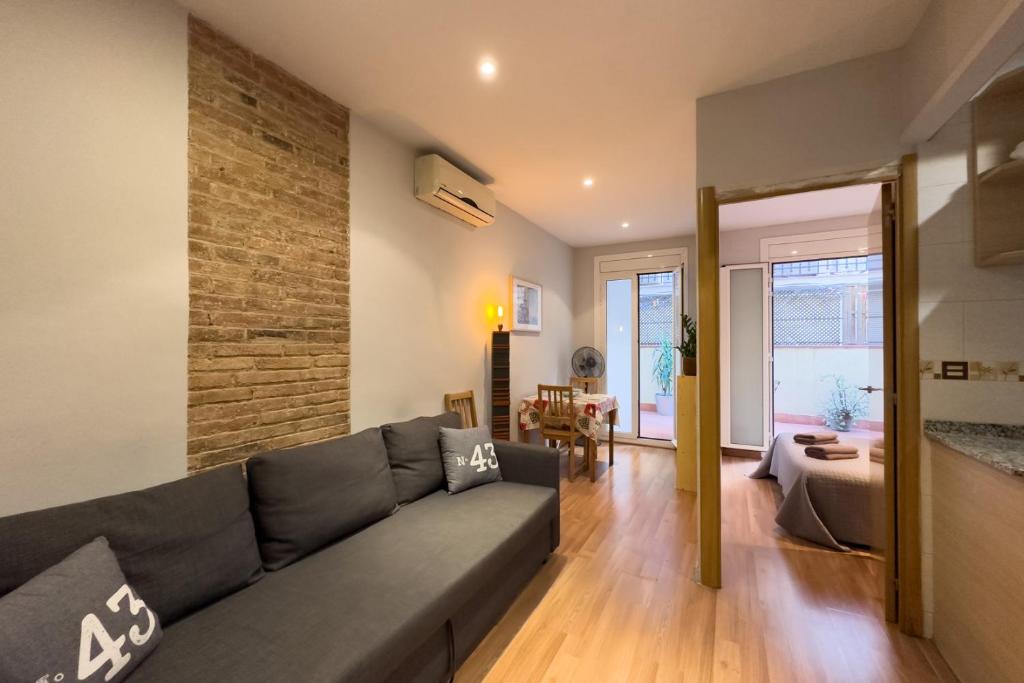 uma sala de estar com um sofá cinzento e uma parede de tijolos em ApartEasy - Central Gracia Apartments em Barcelona